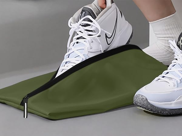 White Nike athletic shoes shown with an olive green fabric product on a light gray surface.