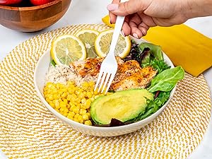 Fork in salad bowl with chicken, corn, avocado, and more.