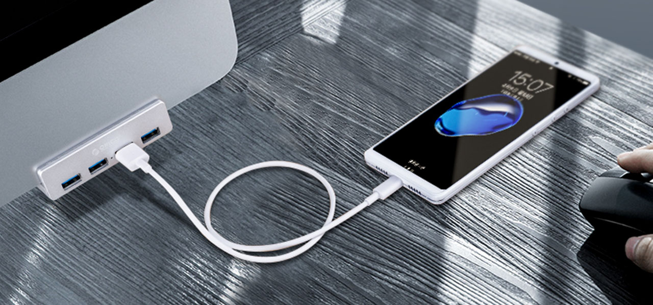 A hub is attached firmly on a montior. A smart phone is connected to the hub's USB 3.0 port via a cable.