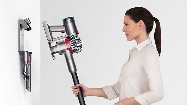 a woman putting Dyson V7 Absolute to the station