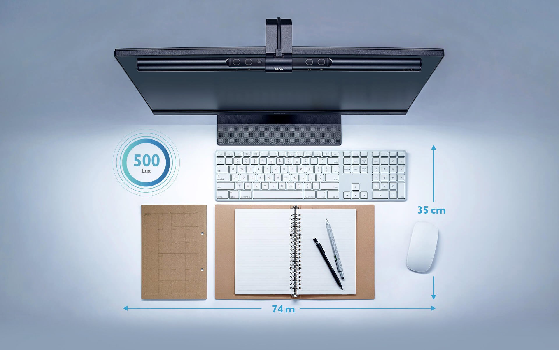 overhead view of the BenQ ScreenBar mounted on a monitor that's in front of a keyboard, 500 Lux graphic, mouse and open notebook with pens