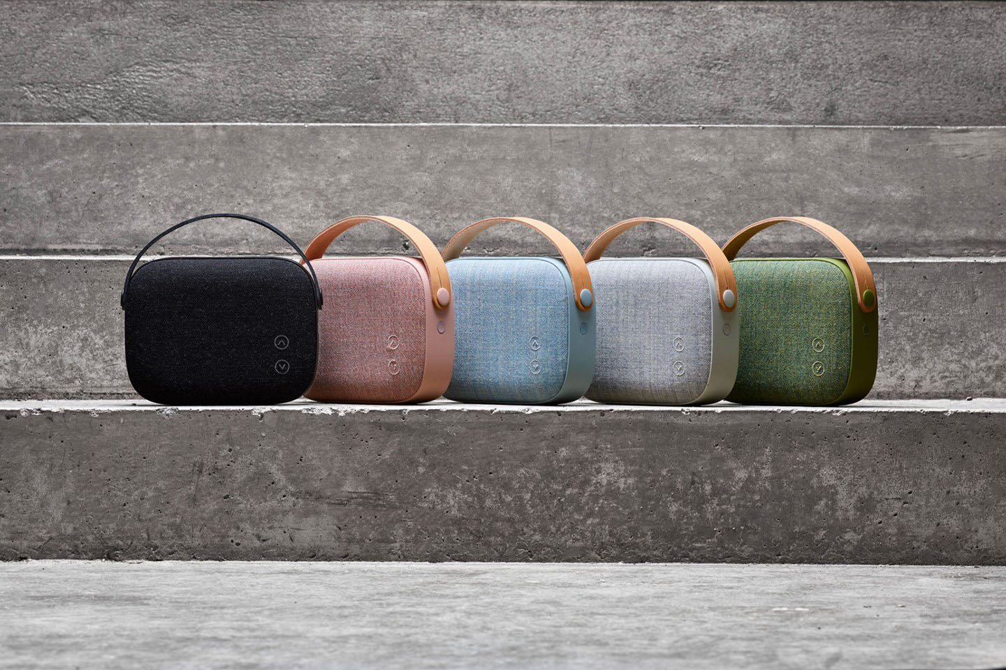 Helsinki Portable Speakers Lined Up at the Bottom Step of a Stone Staircase. Their colors from left to right are: black, pink, blue, gray and green