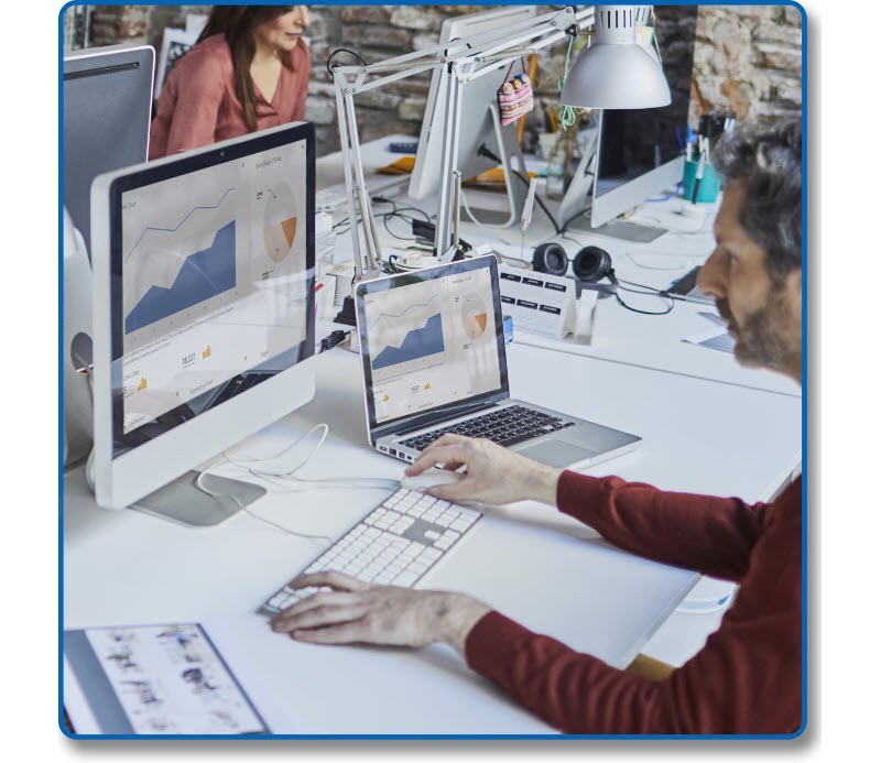 a man working with one desktop and a laptop