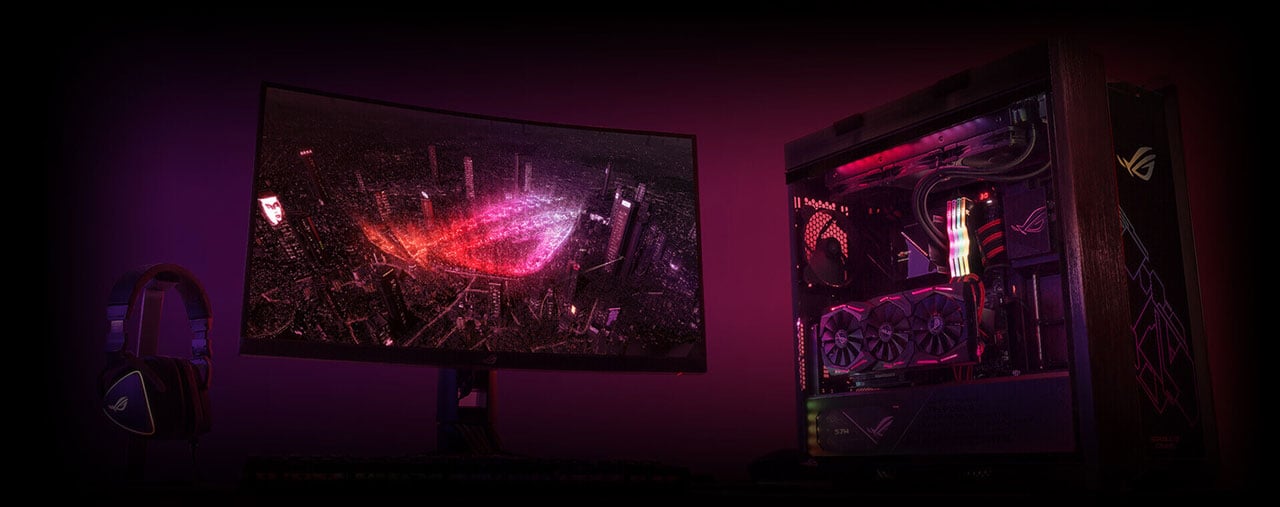 A gaming rig on display, including a monitor, an RGB illuminated desktop, and an ROG headset  