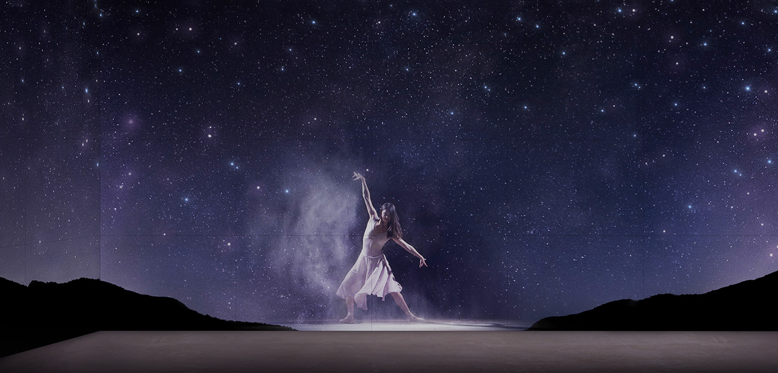 A ballet dancer superimposed to dance between desert mountains on a starry night