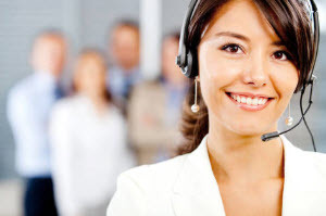 A female customer representative with her headset and 4 blurred-out coworkers behind her.