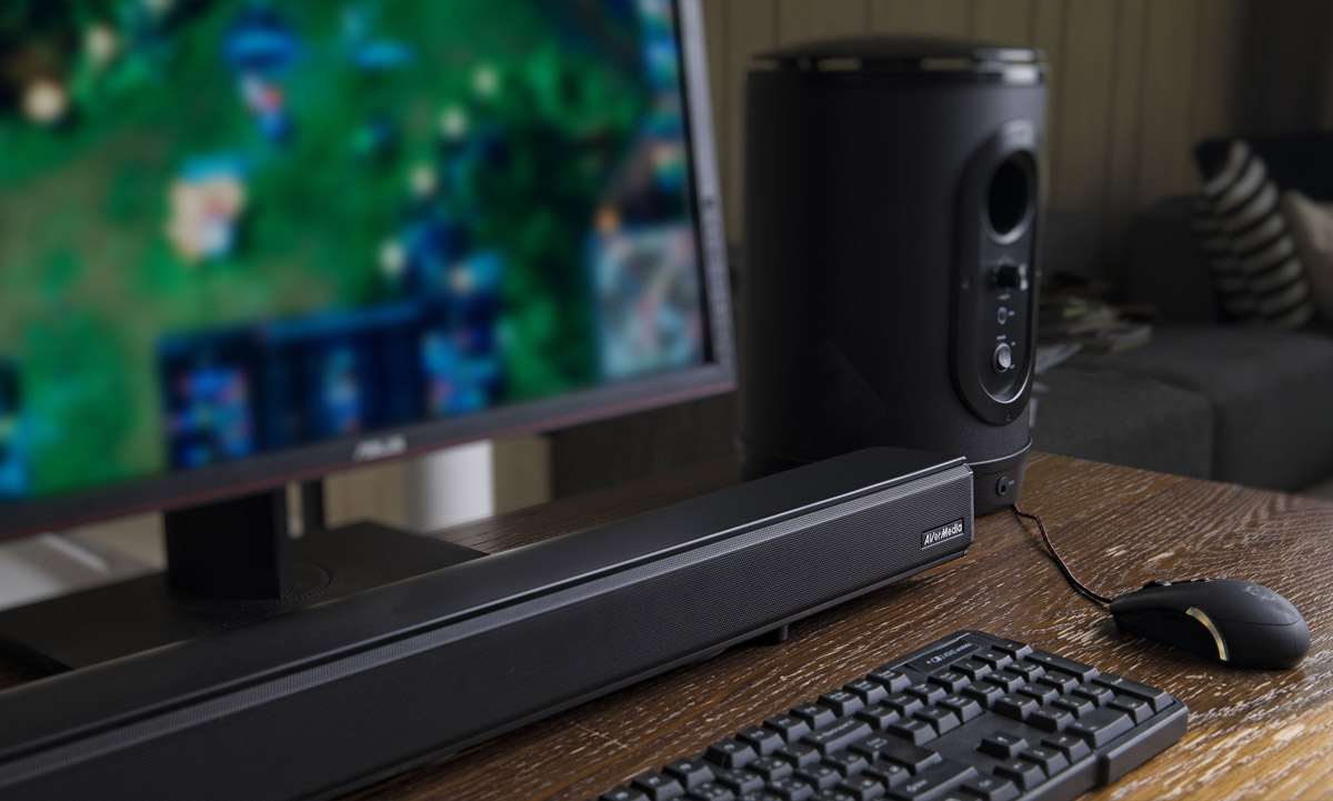 AverMedia Soundbar and Subwoofer on a wooden desk with a keyboard, mouse and monitor angled to the right