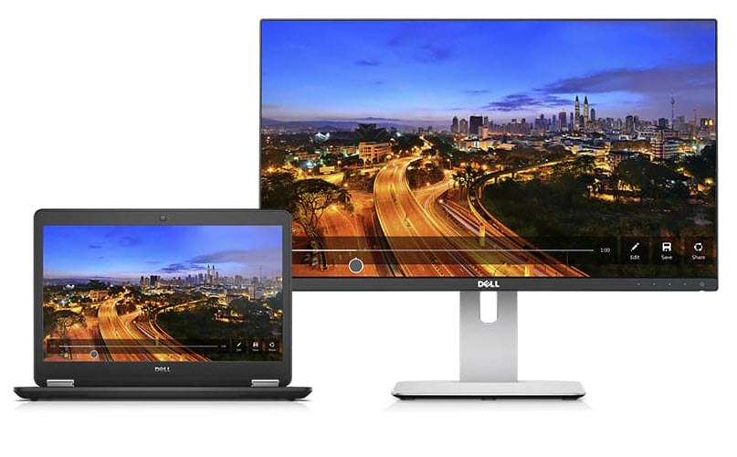 Open Dell Latitude E7450 laptop next to a monitor facing forward. Both screens show a highway with zooming lights at night next to a city skyline in the distance