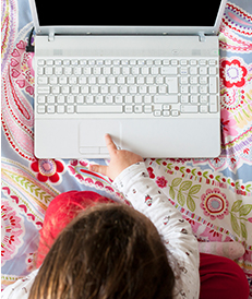 A female child touching the touchpad of her open laptop