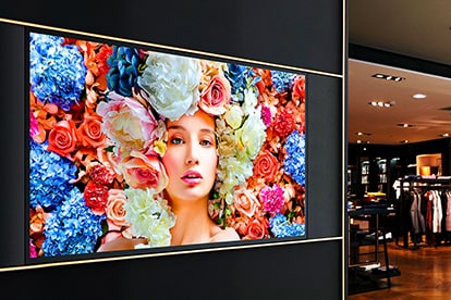 Samsung Display Mounted on a Wall Outside a Clothing Store. The Display Shows a woman with flowers for hair and red, blue and pink flowers all behind her