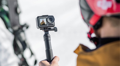 A snowboarder with his gear to the side, taking a selfie with the Osmo Action