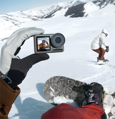 A snowboarder taking a break to take a selfie with their Osmo Action on a snow-covered mountain