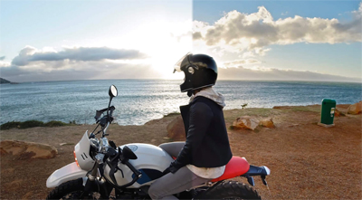 A motorcyclist taking a break at a cliffside to watch the sun set by the ocean
