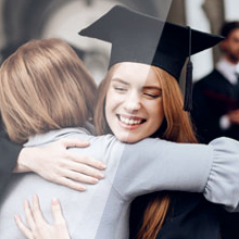 a female graduate is hugging another woman