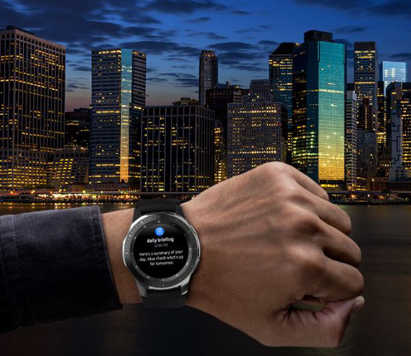 A hand with a watch on is raised up during night against a backdrop of skyscrapers
