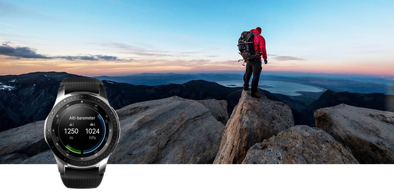 A watch is against a backdrop of a man standing on rocks on seaside.