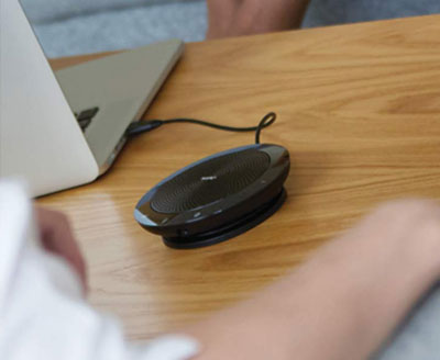   The Jabra Speak 510 connected to a laptop on a wood desk 