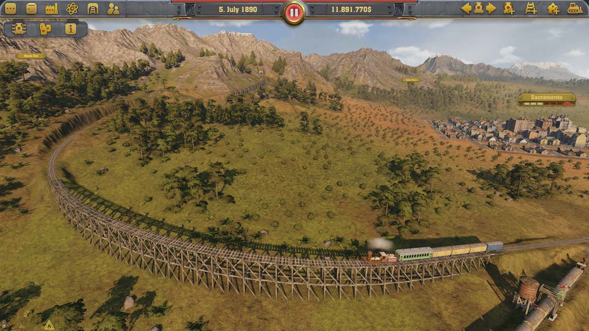 Overhead shot of a train on a wooden railway passing through a forest next to a mountain range