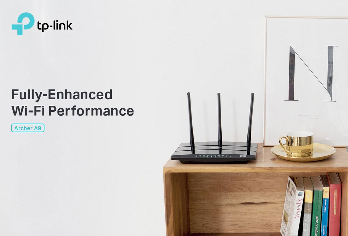 tp-link Archer A9 on a wooden shelf with books, a gold coffee mug on a platter and a picture frame with the letter 