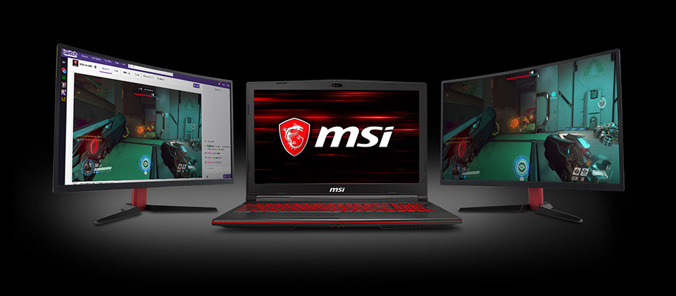 Gigabyte GL63 Gaming Laptop in between two monitors, the left monitor shows a twitch stream of Overwatch while the right monitor has the actual Overwatch gameplay