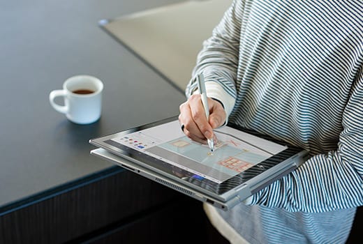 A person using a compatible pen on the HP ENVY in tablet mode