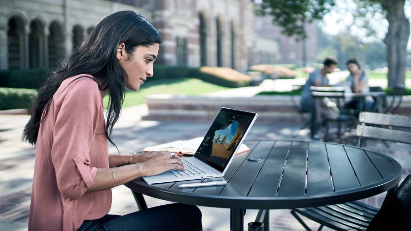 a woman typing on Surface Book placed on a desk outdoors