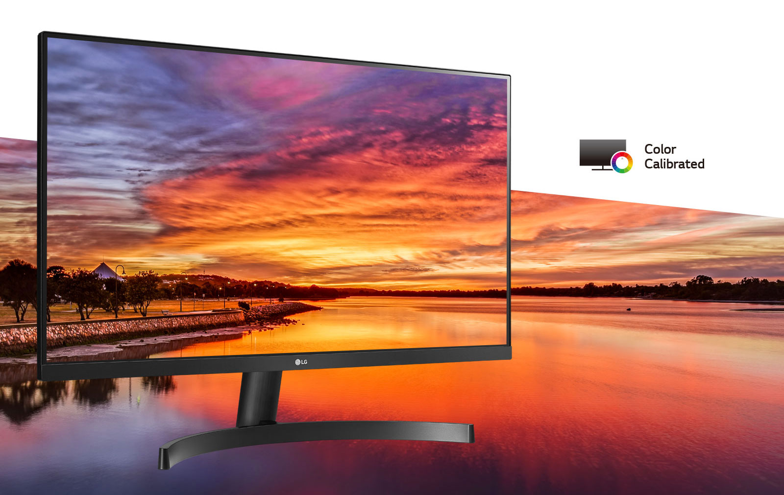 LG 22MK600M-B angled to the right with its screen blending into a lakeside view during a pink, yellow and purple sunset. At the top right is the Color Calibrated Monitor icon