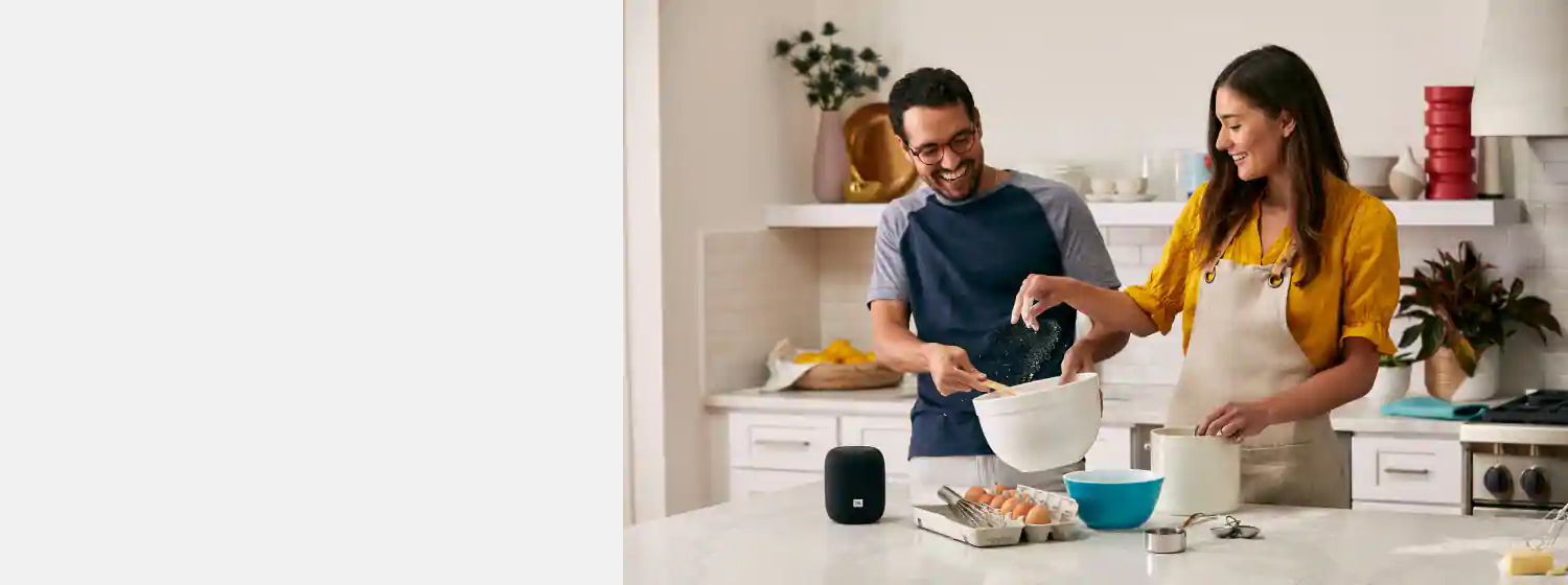 JBL Link Music Wi-Fi speaker is playing music, a man and a woman are cooking food.