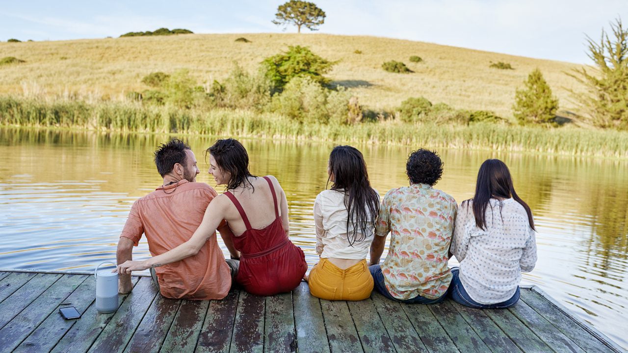 Five people sitting by the lake listening to wonderful music with Bose Portable Home Speaker