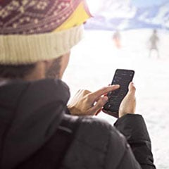  rear view of a man in snow filed operating his phone  