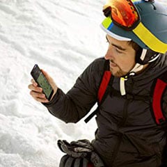   front angle view of a man in snow field watching his phone 