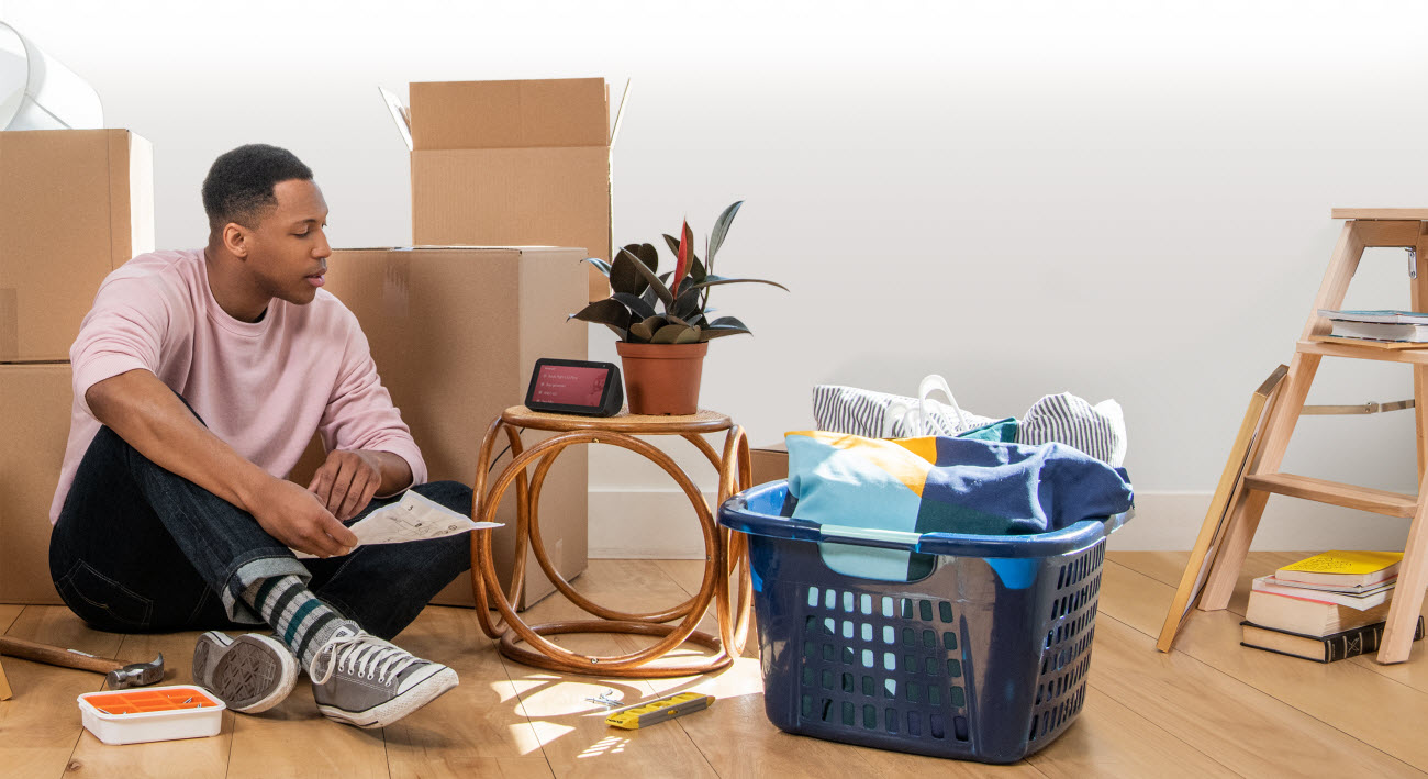 a man sitting on the floor with Echo Show 5 placed on a chair