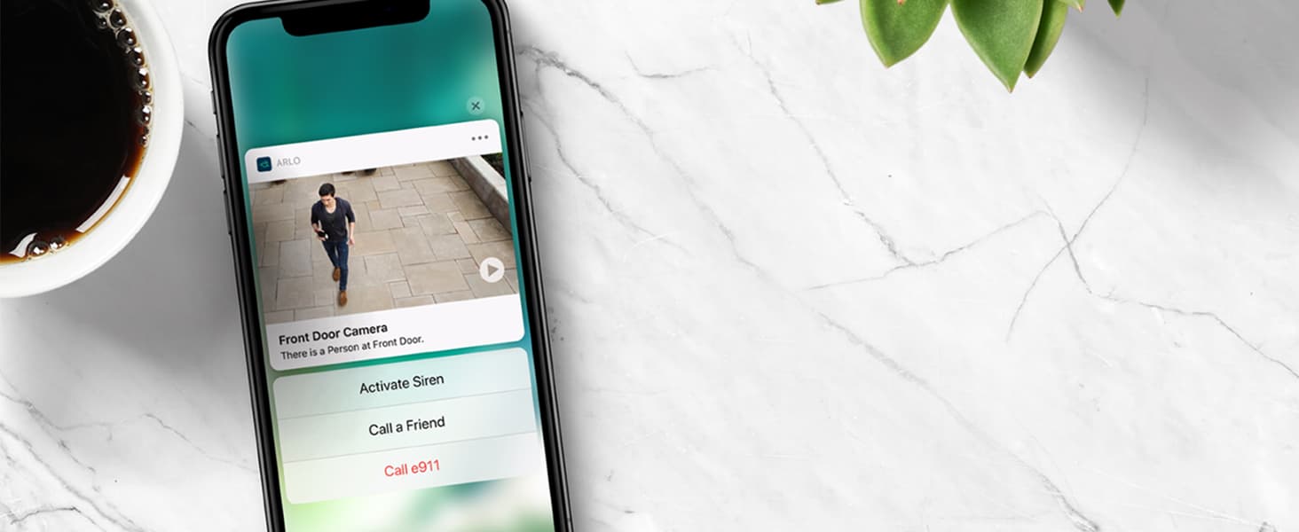 Arlo Smart Premier App on a smartphone, next to a cup of coffee