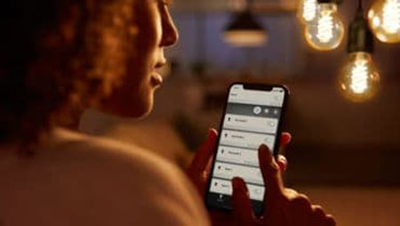 a woman control Philips Hue ST19 E26 bulbs via the Hue Bluetooth app on her smartphone