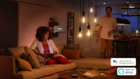 a woman sitting on the couch controlling smart bulbs by her voice