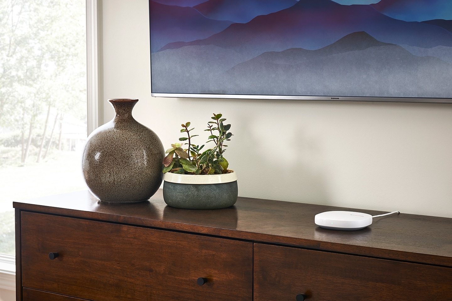 Samsung SmartThings Hub on Top of a Cabinet Under a Mounted TV in a Living Room