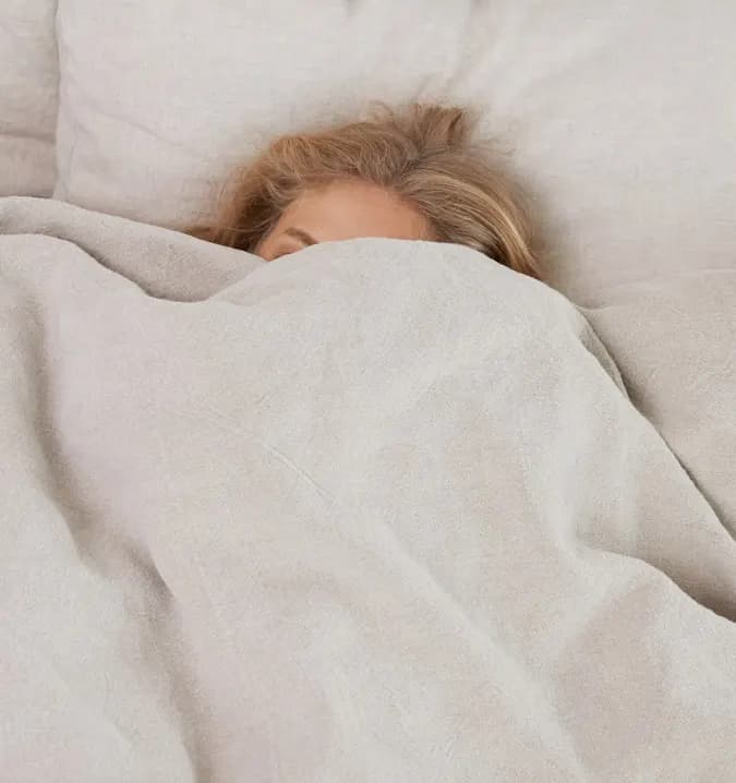 a woman covering her head with a gray blanket