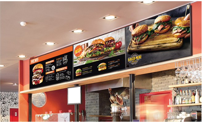 Three LG displays mounted above a burger restaurant showing menu options and food photos