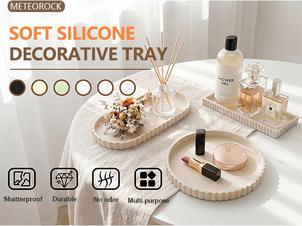 Text reads 'METEOBBLOCK', 'SOFT SILICONE DECORATIVE TRAY'. Beige soft silicone tray with cosmetics and jewelry. Six color options displayed. Bottom icons indicate: Waterproof, Dustproof, Durable, Multi-purpose.