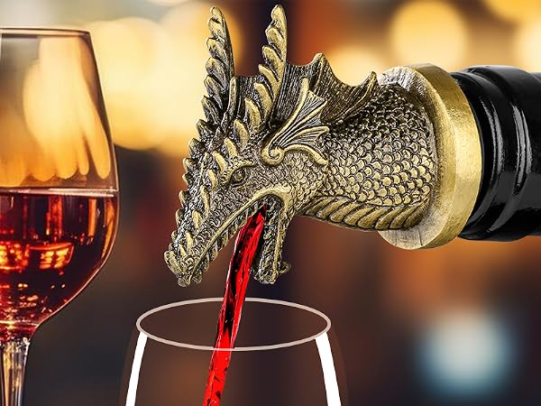 Decorative dragon-shaped wine pourer/aerator in antique gold finish, shown pouring red wine into a glass, with filled wine glass in background.