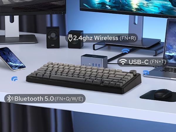 a desk with a keyboard, mouse, speakers, and other electronics.