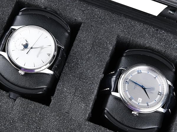 Two analog watches with silver cases and light-colored dials displayed in protective black foam cushioning.