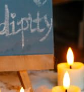 Close-up view of two lit candles glowing in a dark setting with partial text visible in background.