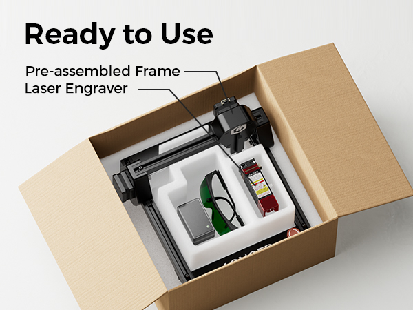 Pre-assembled laser engraver frame in an open cardboard box. Package includes safety glasses, tools, and instructions, demonstrating the 'Ready to Use' concept.