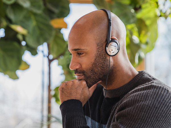  African-American man wearing the Panasonic RP-HT21M on-ear headphones while typing on laptop