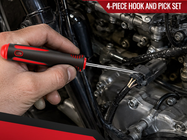 Pick tool positioned beside an electrical connector on a motorcycle engine.