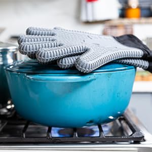 Gray Ekogrips gloves placed on a hot pot over gas stove.