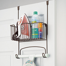 bronze over the door rack with basket holding iron and bottles attached to back of a white door