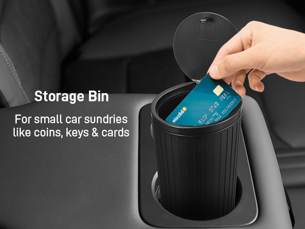 Black cylindrical storage bin for car sundries like coins, keys, and cards. Hand demonstrating opening lid with credit card visible inside.