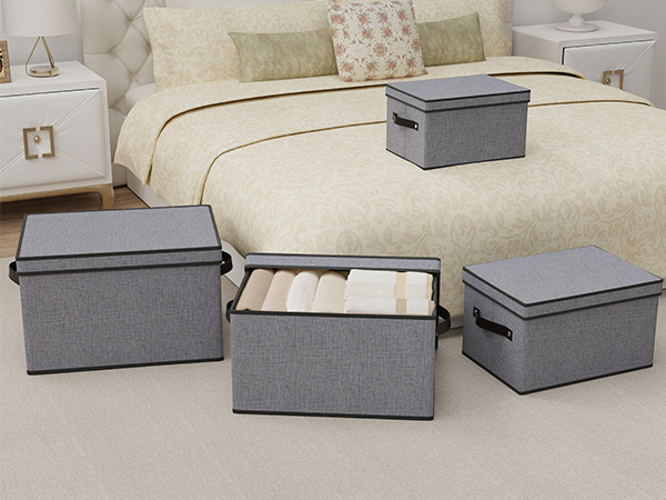 Set of three gray fabric storage boxes with lids, displayed on beige upholstered furniture, showing organized storage solution.